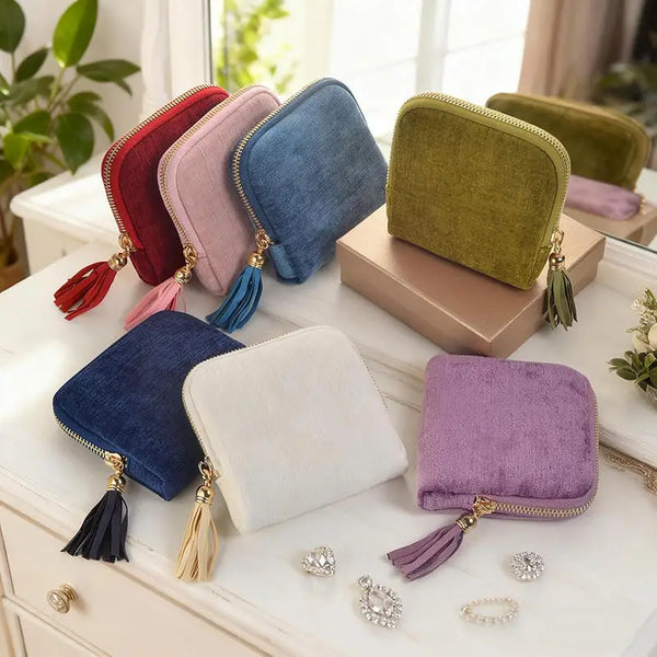 A collection of velvet jewelry storage pouches in various shades including pink, blue, green, and purple with gold tassels.