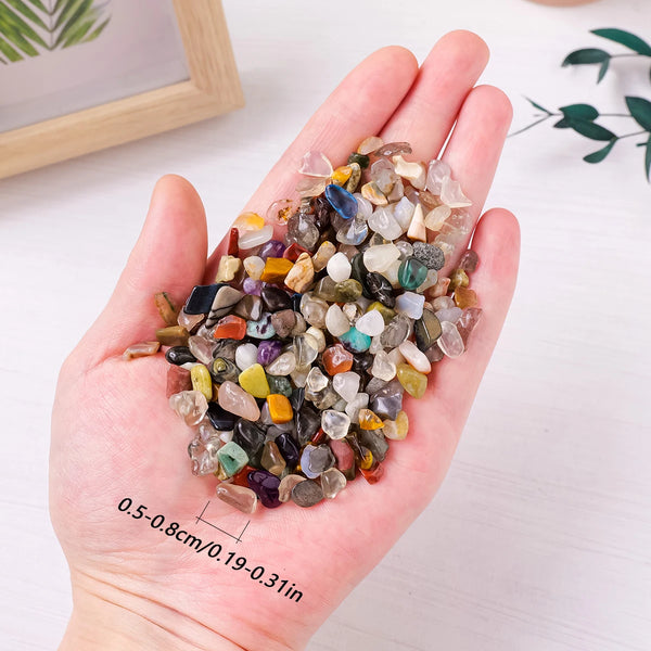 A hand holds a pile of natural crystal gravel and stones for decor and spirituality.