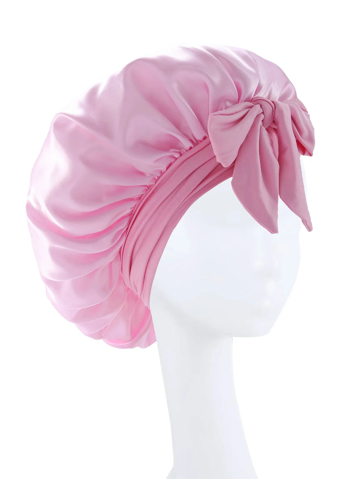 Pink silky satin sleep bonnet tied with a bow displayed on a white mannequin head.