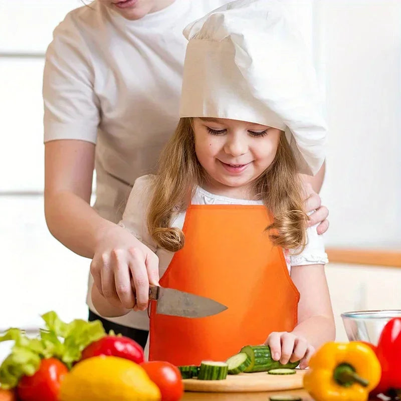 A young girl is wearing an orange non-woven craft apron while being assisted by an adult, with fresh produce nearby.