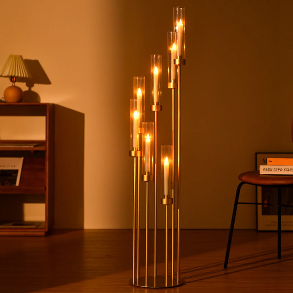 A tall, slender gold floor candelabra centerpiece with seven vertical arms holding glowing candles.