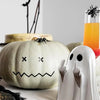 A white pumpkin decoration is shown next to a white ghost statue and a black spider.