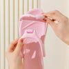 Une main tient une sandale EVA rose pliable, montrant la texture et le design de la lanière.