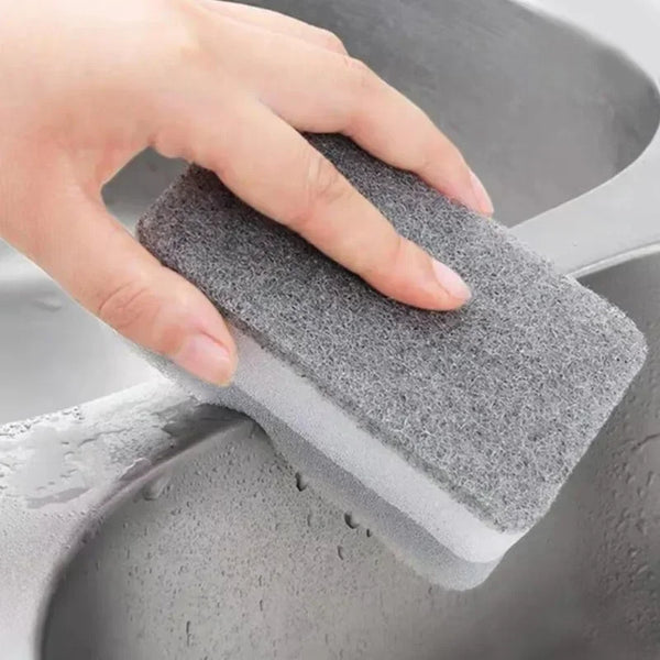 A hand is using a gray, reusable double-sided kitchen cleaning sponge inside a sink.
