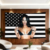 A woman posing in front of a black and white striped American flag banner.