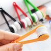 A hand holds an orange cleaning brush with white bristles, next to a set of colorful microfiber eyeglass cleaning brushes.