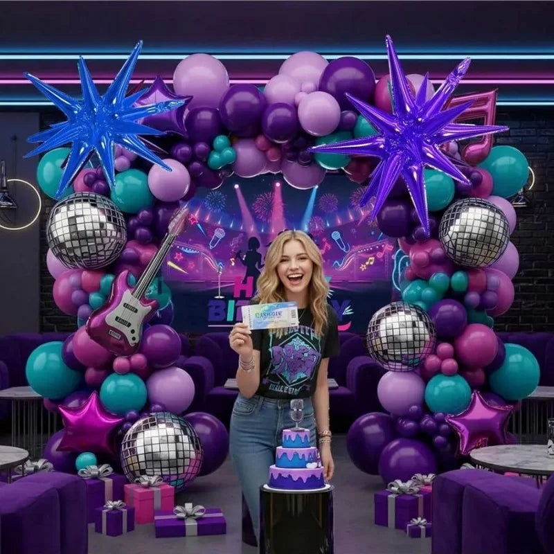 Eine Frau steht vor einem lila und türkisen Ballonbogen, dekoriert mit silbernen und lila Ballons.