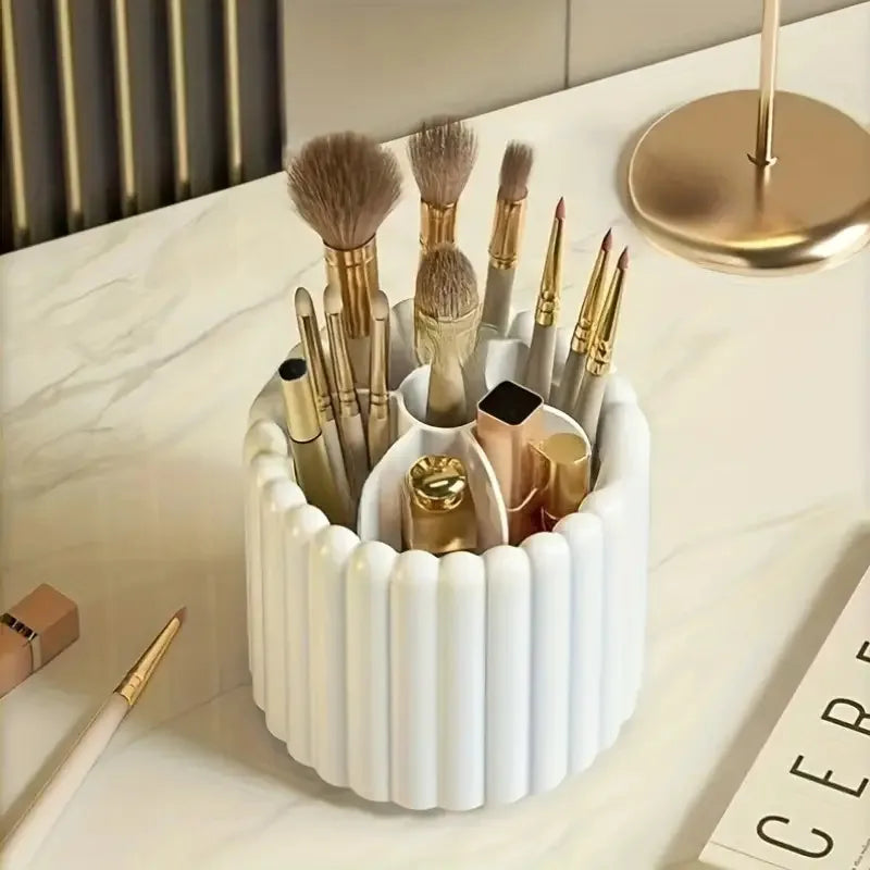 A white cylindrical organizer holds various makeup brushes and applicators on a marble surface.