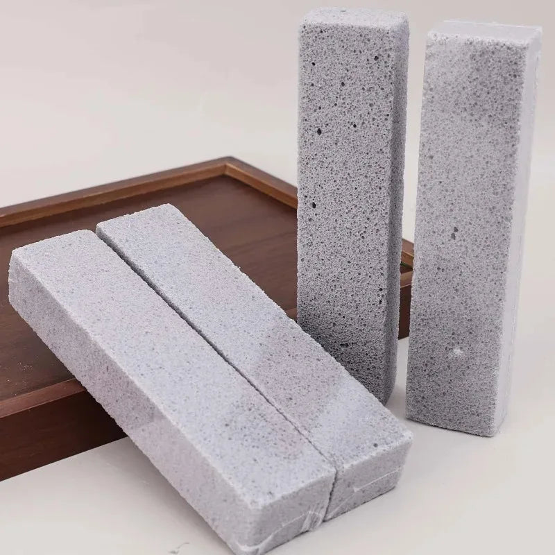 Two rectangular gray pumice stone sticks are displayed on a wooden tray.