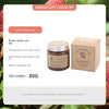 A brown glass jar candle labeled Litchi white tea with a cardboard box in the background