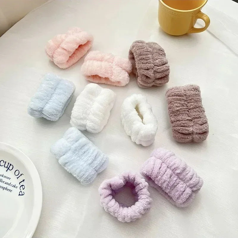A set of pink, lavender, and gray microfiber wrist sweatbands for face washing and skincare displayed on a white surface.