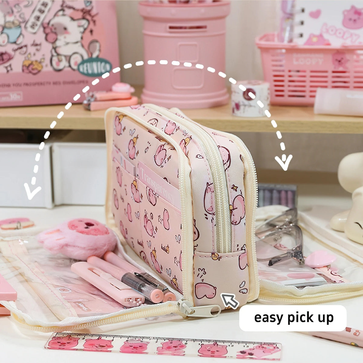 A pink dual-sided transparent pencil pouch is shown with pencils and pink accessories on a wooden surface.