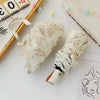 A white embroidered sun umbrella is shown next to a wooden stick and decorative beads.