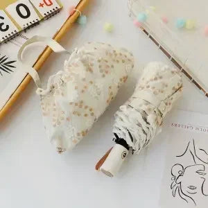 A white embroidered sun umbrella is shown next to a wooden stick and decorative beads.
