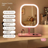 A pink LED desktop vanity mirror with a circular light frame is shown on a white surface.