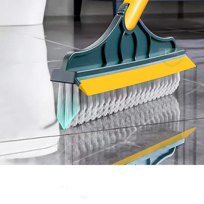 A close-up view of a teal and yellow 2-in-1 floor scrub brush being used to clean a reflective floor surface.