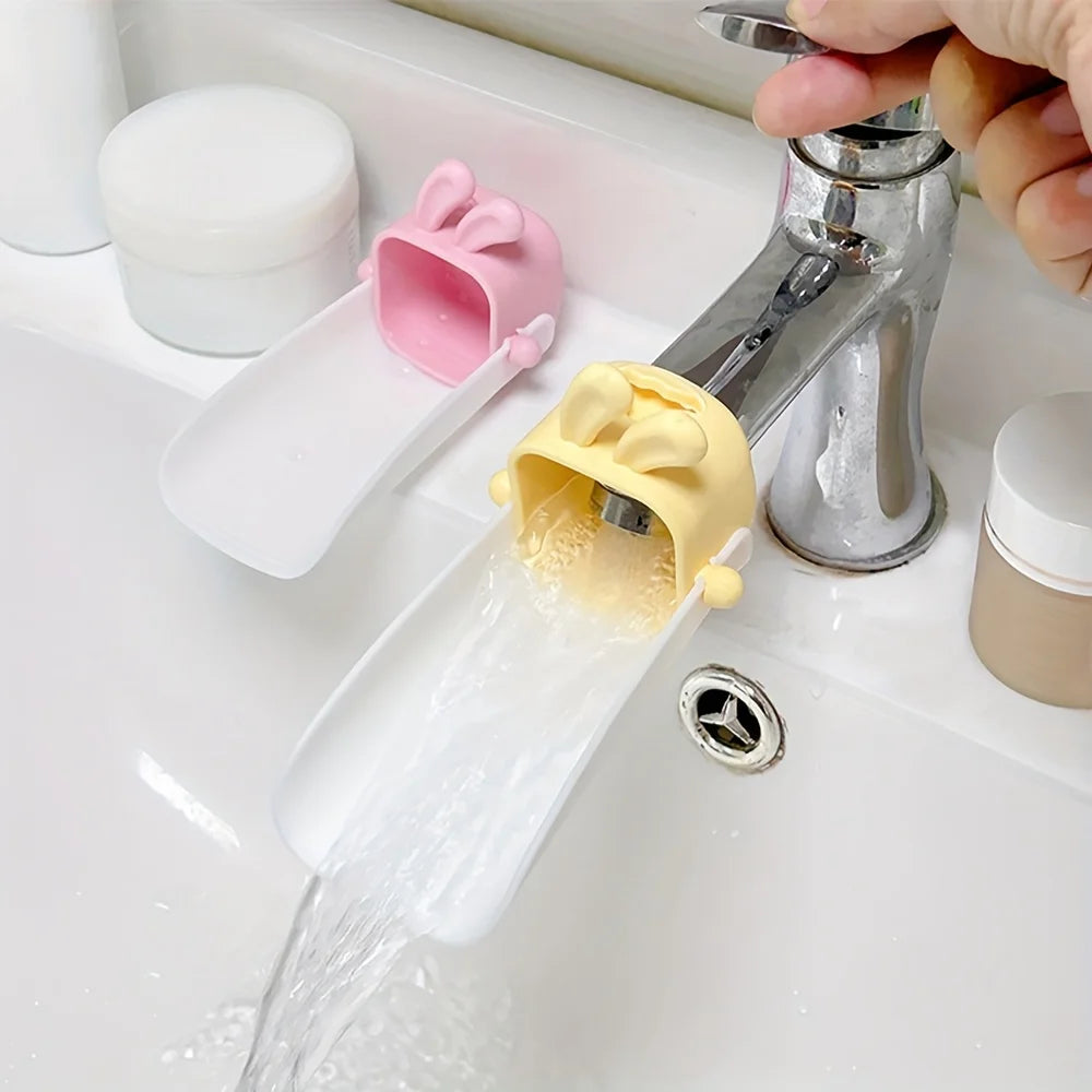 A faucet extender with a cute pink rabbit design is shown dispensing water into a white sink.