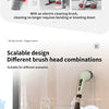 A person is using an electric cleaning brush with a long handle and various brush heads on a glass surface.