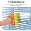 An orange cleaning brush is shown cleaning the slats of a blue horizontal blind.