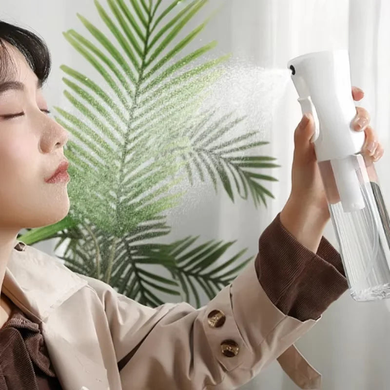 A person is using a white refillable continuous spray bottle to mist a green leafy plant.