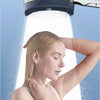 A woman is under a filtered high-pressure shower head, with water spraying onto her face and hair.