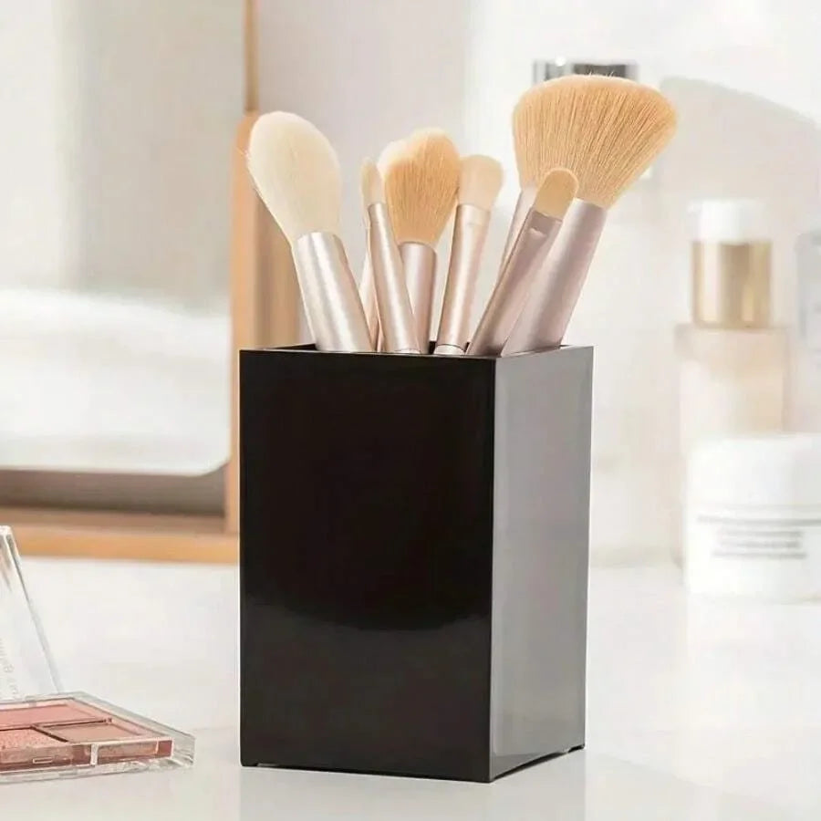 A black cosmetic storage organizer holds several makeup brushes with light beige and pink bristles.