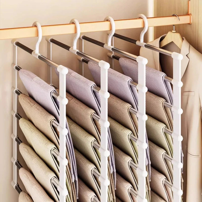 A white multi-layer hanger organizer holding folded beige and purple pants.