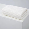 White coral velvet bath towel folded neatly on a white surface