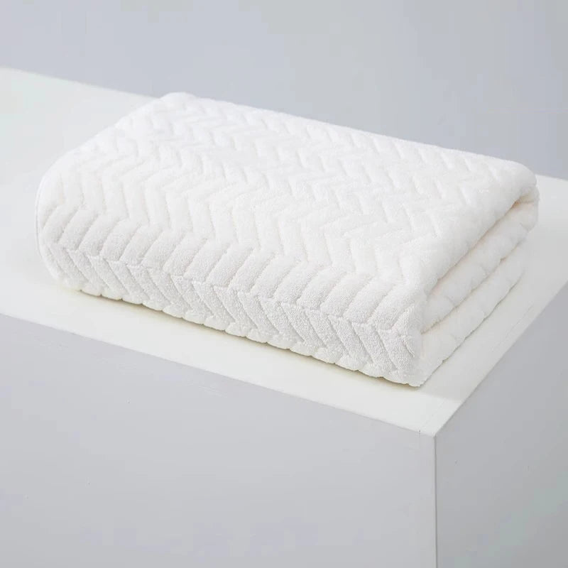 White coral velvet bath towel folded neatly on a white surface