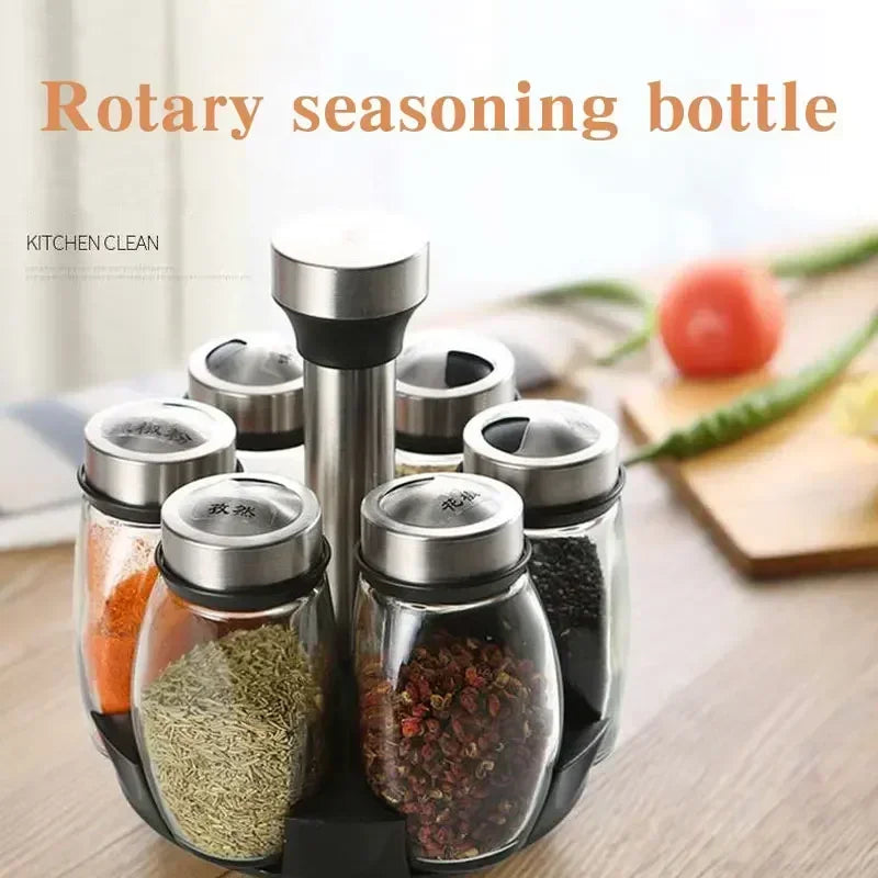 A rotary seasoning bottle rack displaying various spices in glass jars with stainless steel lids.