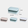 A set of three transparent drainage soap dishes in pink, light blue, and white.
