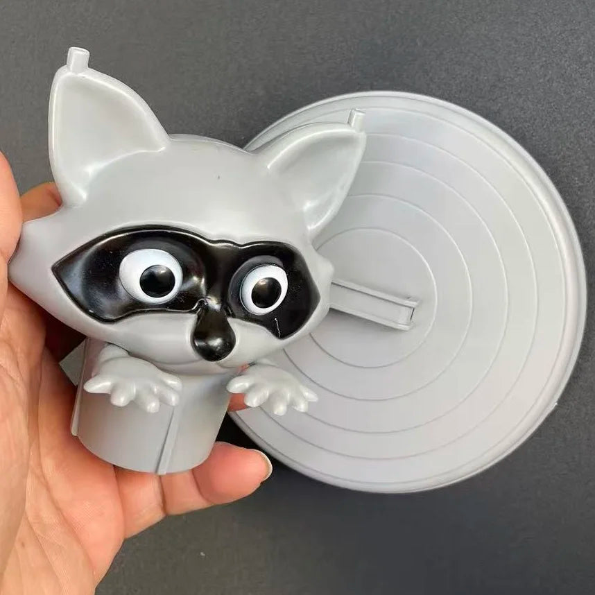 A gray decorative toilet paper holder shaped like a fox head with black eyes and ears, shown in a hand.