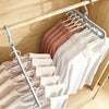 A set of three pink and white folded plastic hangers hanging on a wooden rod.
