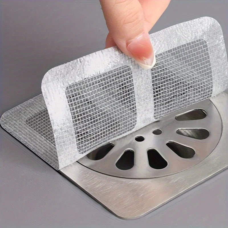 Eine Hand legt einen Netz-Auffangfilter über ein Metall-Spülbeckenabflussgitter.