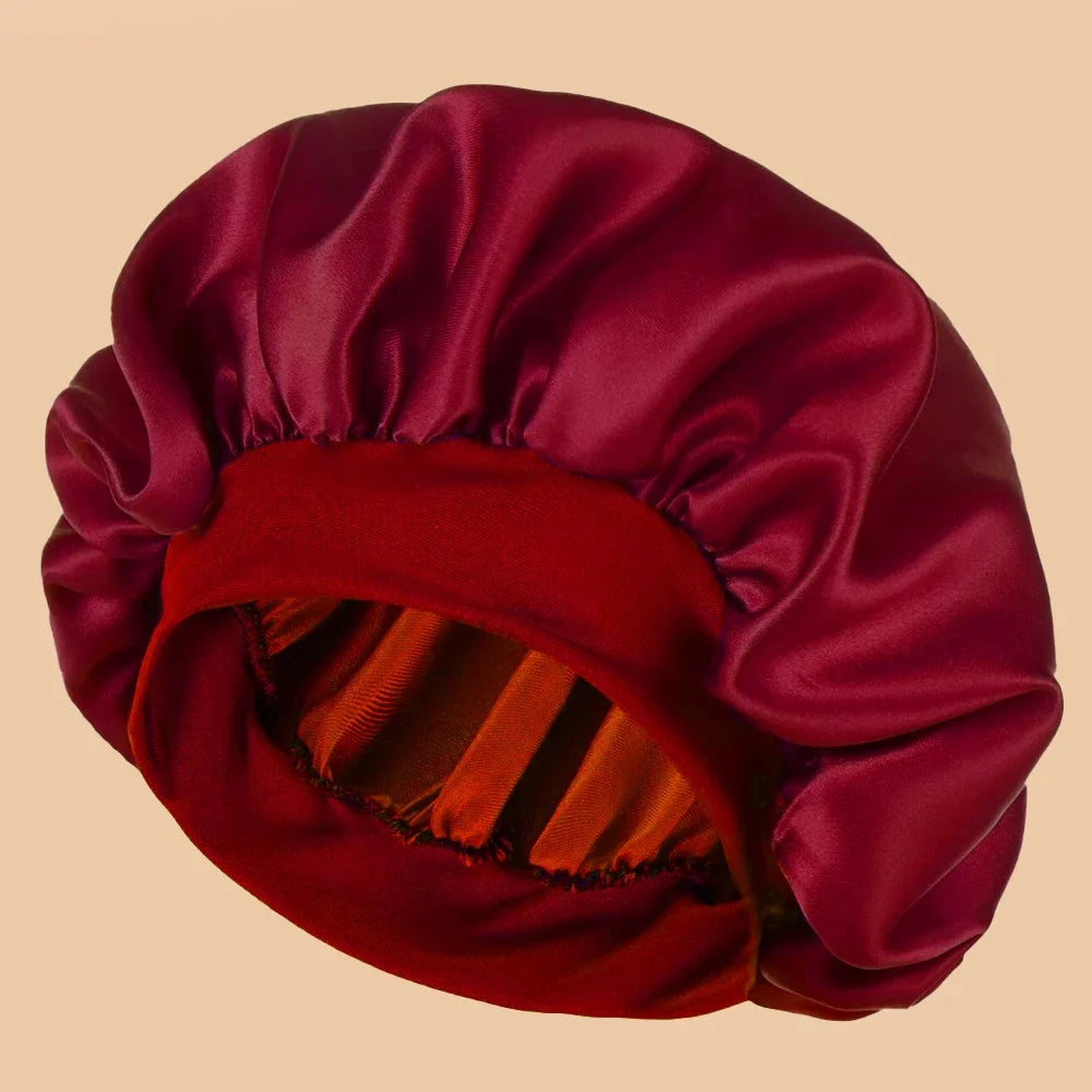 A deep magenta satin wide brim shower cap folded and displayed against a neutral background.