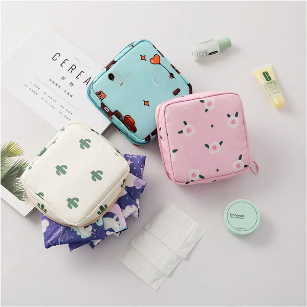 A pink floral nylon sanitary pad storage pouch next to a white pouch and some skincare products.