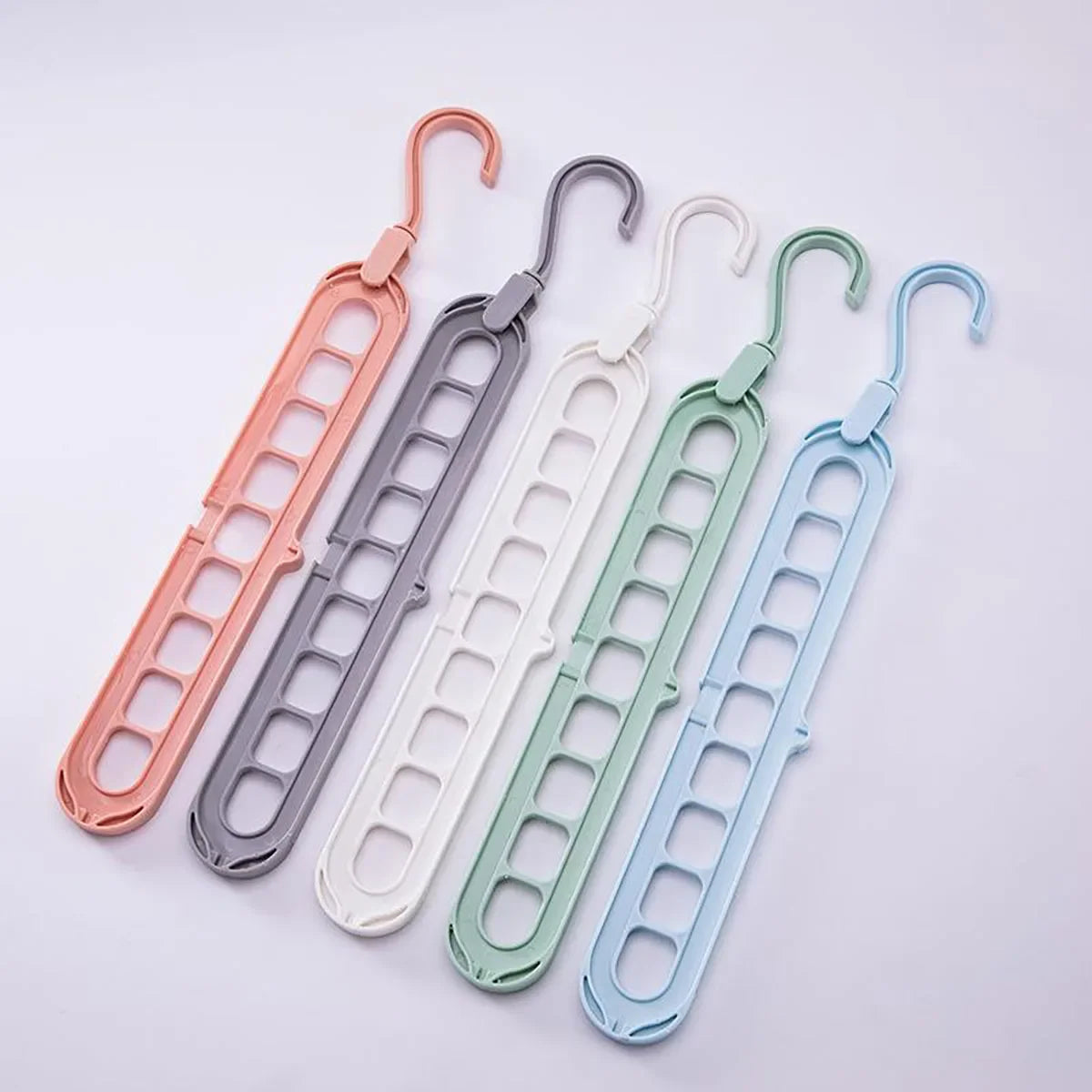 A set of five collapsible rotating clothes hangers in various pastel colors, including pink, gray, white, green, and light bl
