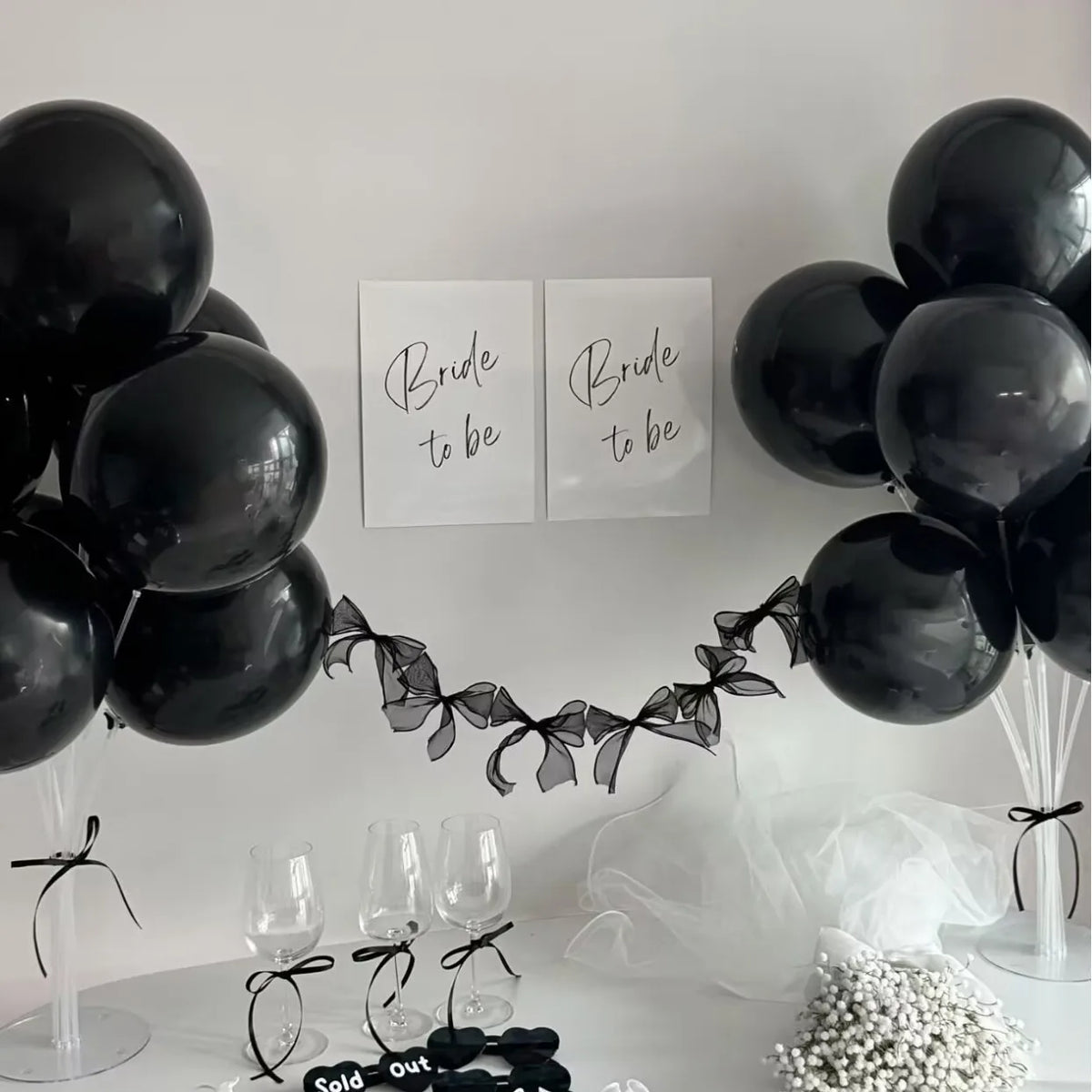 A black balloon garland set with bowknot accents displayed on a white surface.