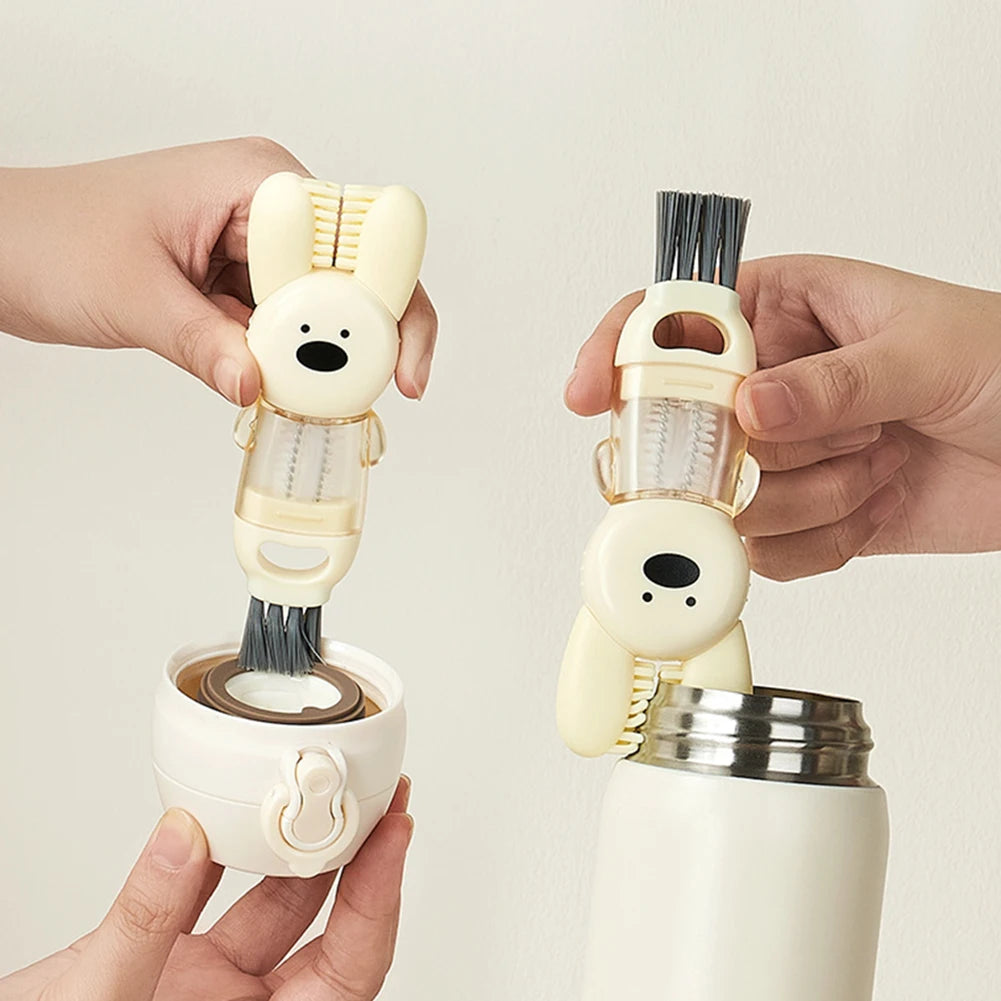 A hand holds a white portable cup and bottle cleaning brush set with a brush and a bunny-shaped grip.