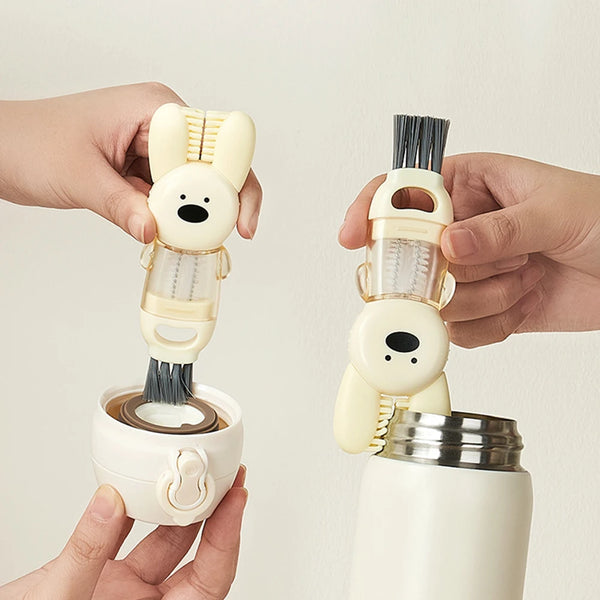 A hand holds a white portable cup and bottle cleaning brush set with a brush and a bunny-shaped grip.