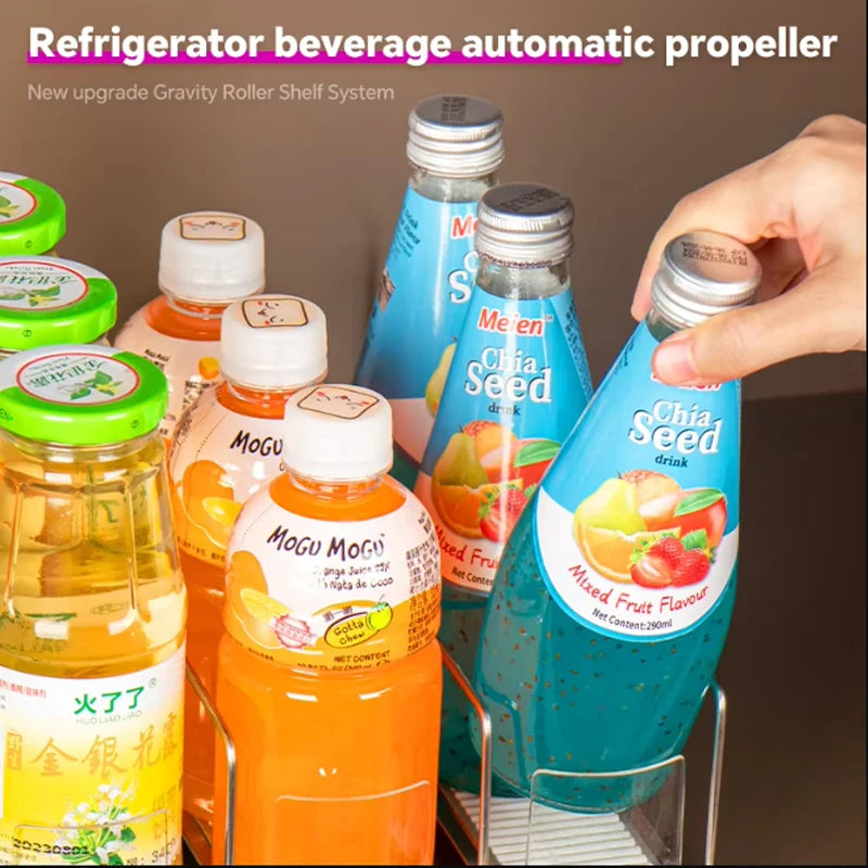 A hand is dispensing a mixed fruit flavor drink from an automatic propeller dispenser in a refrigerator organizer.