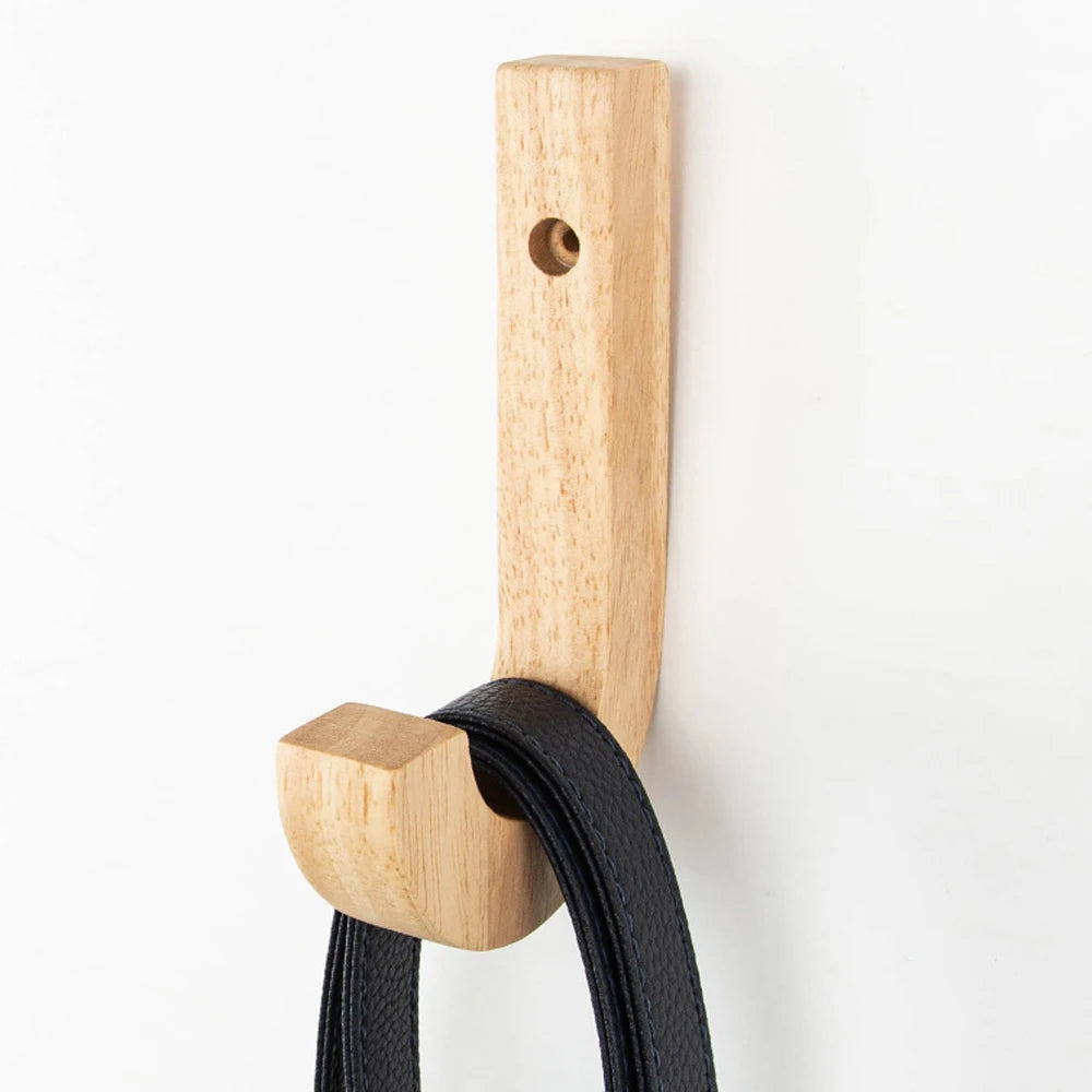 Natural oak wood wall hooks with screws mounted on a white surface.