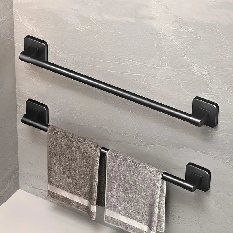 Black wall-mounted towel rack with a gray towel hanging on a light gray wall.