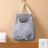 Gray mesh wall mounted garbage bag storage organizer hanging on a beige wall.