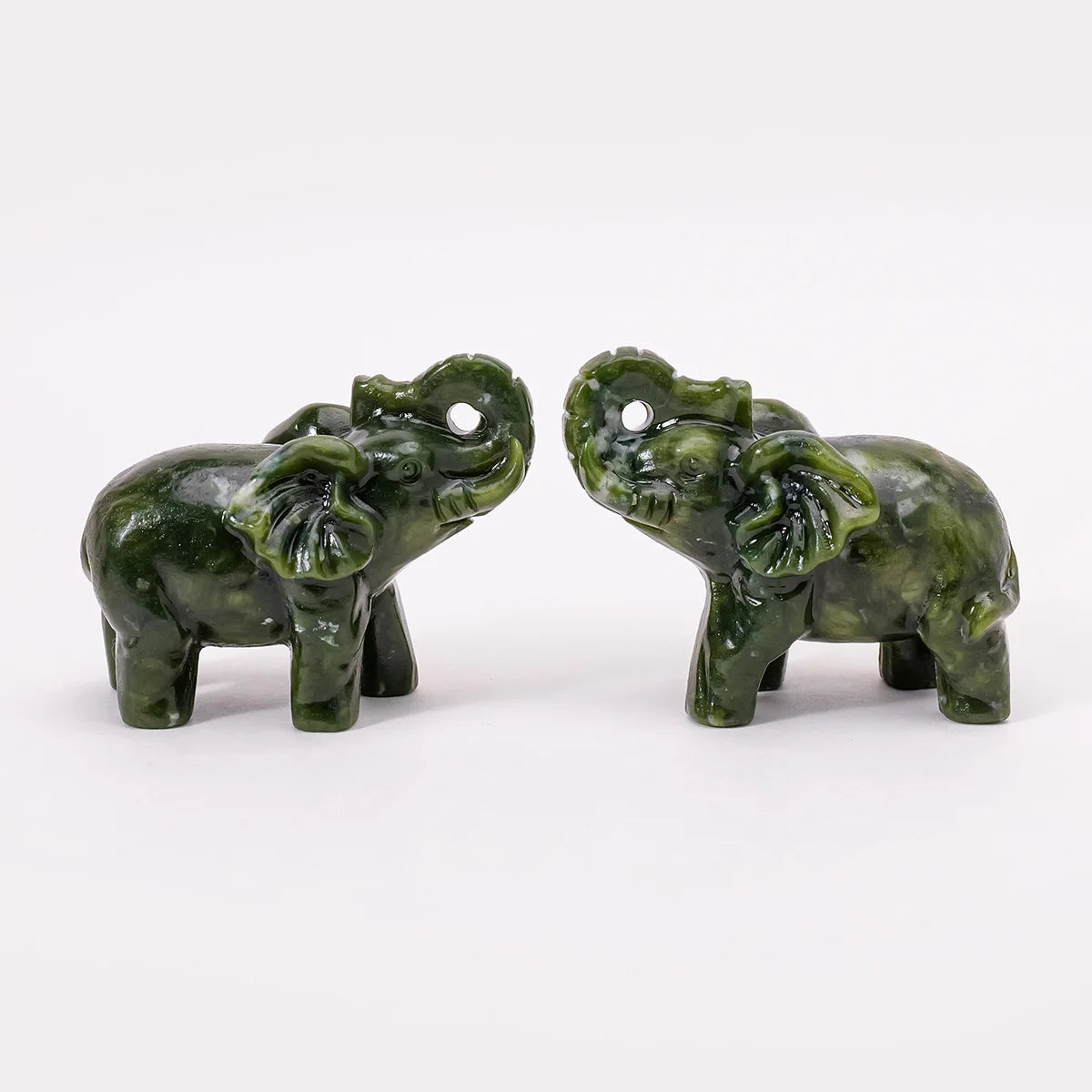 A pair of hand-carved jade elephant statues for home decor, dark green in color.