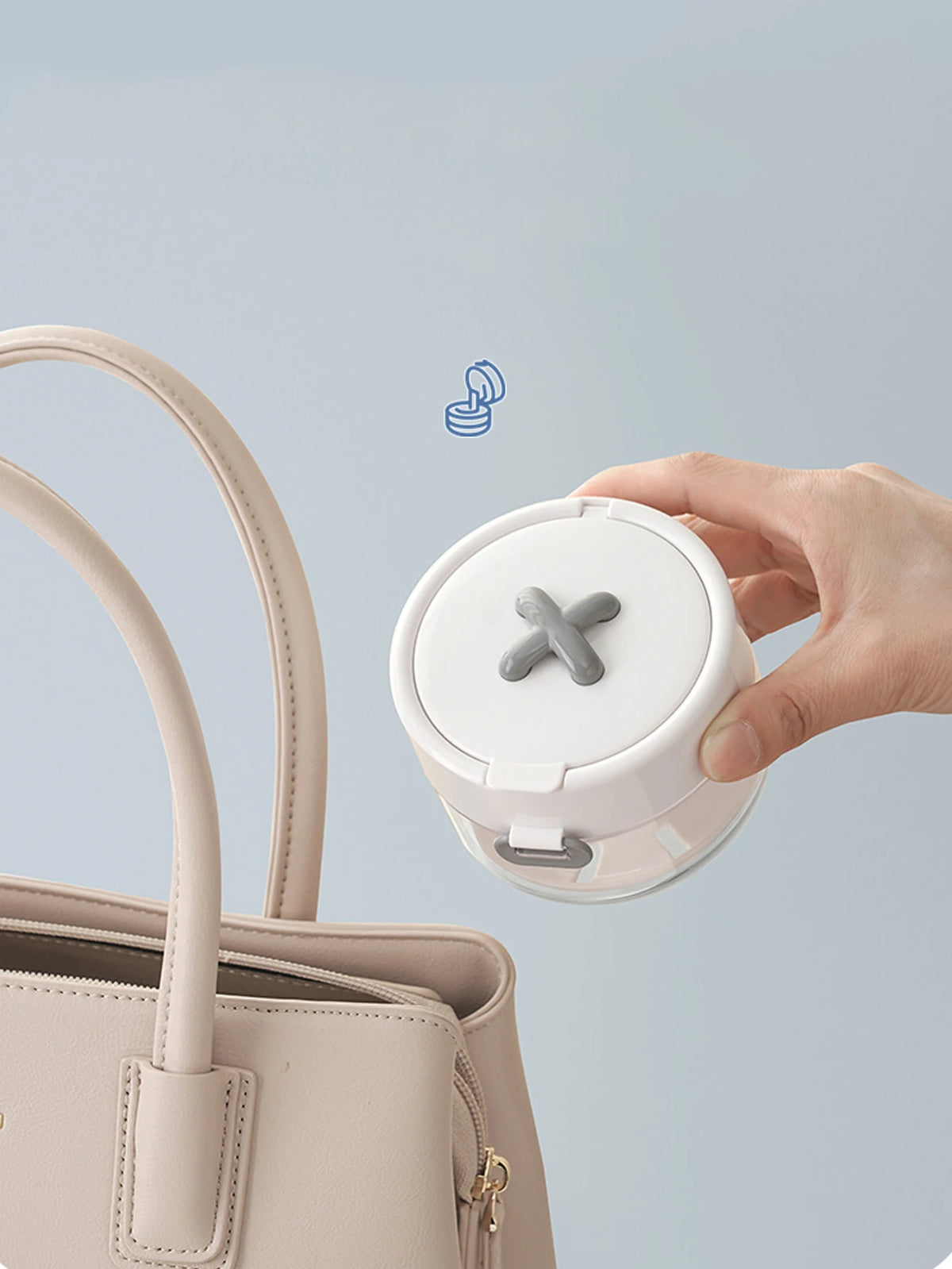 A hand is holding a white portable multi-tool organizer for dental appliances, positioned above a light pink handbag.