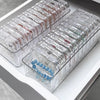 A clear plastic jewelry organizer box filled with multiple small compartments and jewelry items.