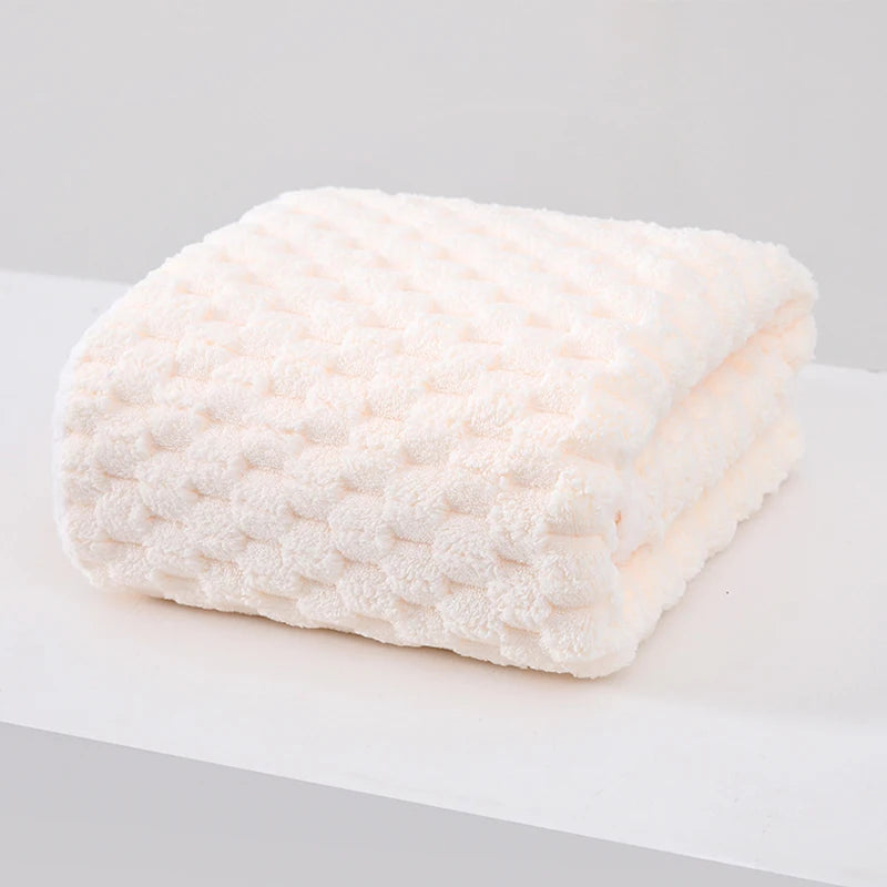 A thick, white microfiber bath towel with a textured, quilted surface is displayed on a white surface.