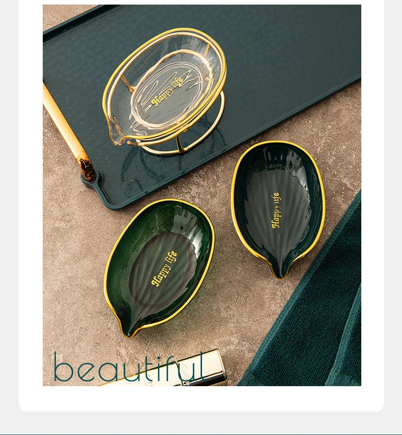 A set of decorative leaf soap dishes in gold and dark green ceramic resting on a slate tray.