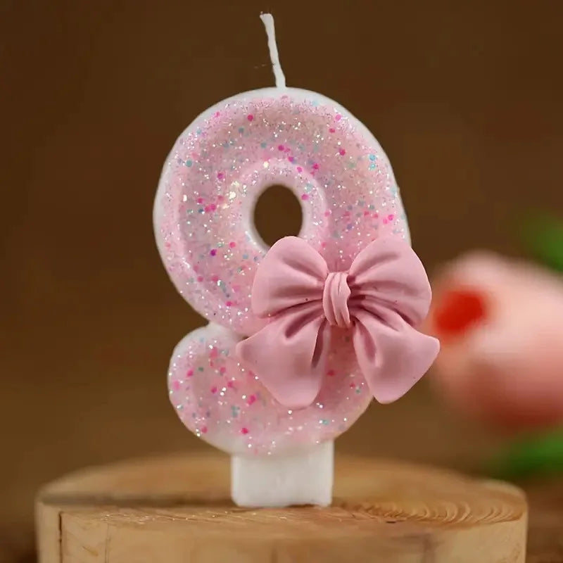 Pink glitter number 8 birthday candle with a pink bow on a wooden surface